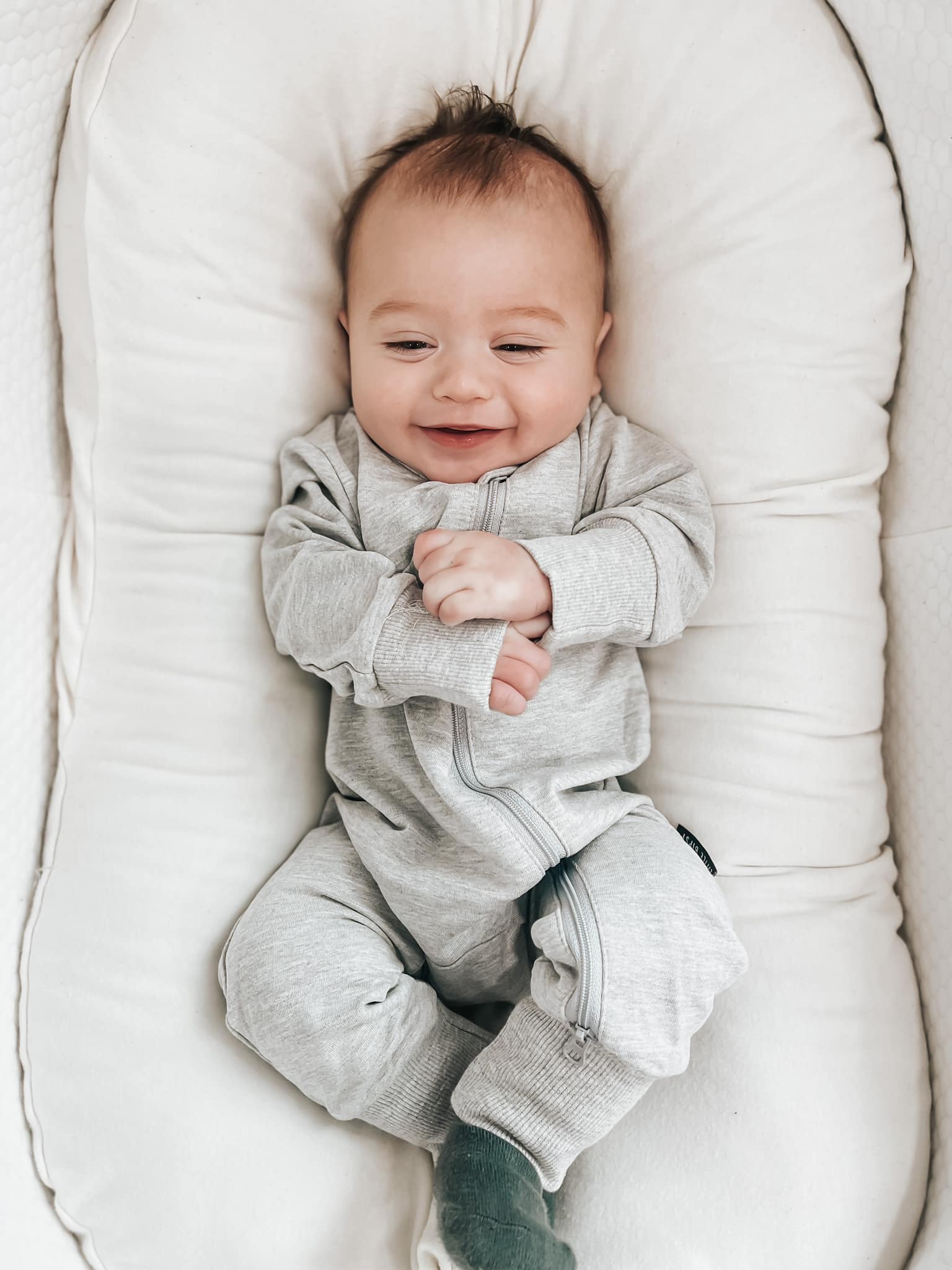 Smiling baby in two-way zip grey romper
